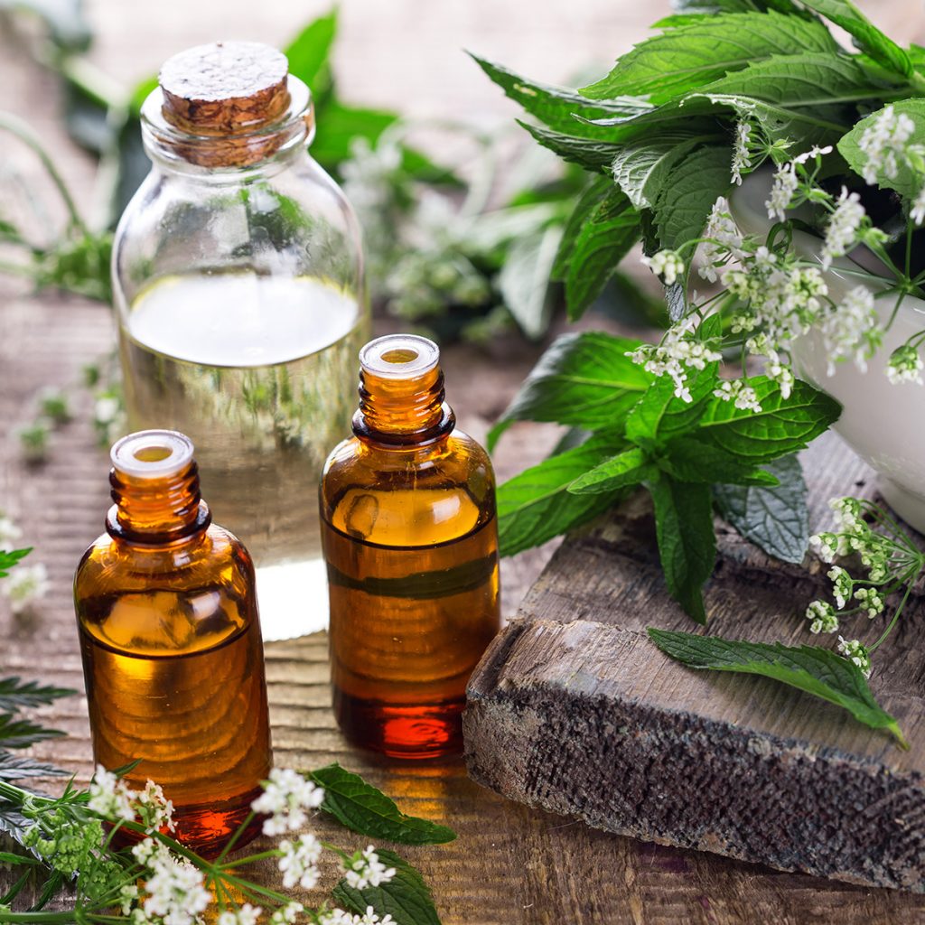 staged aromatherapy setup with two bottles and wood with greenery