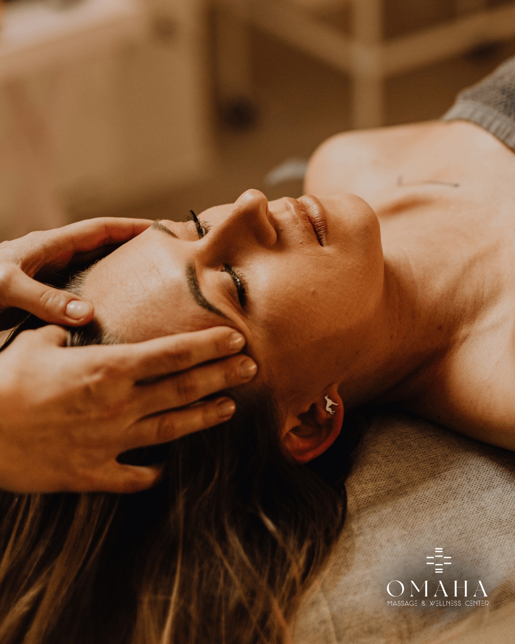 A woman receiving a relaxing head massage at an Omaha massage spa, showcasing professional therapeutic services offered at Omaha Massage and Wellness Center.