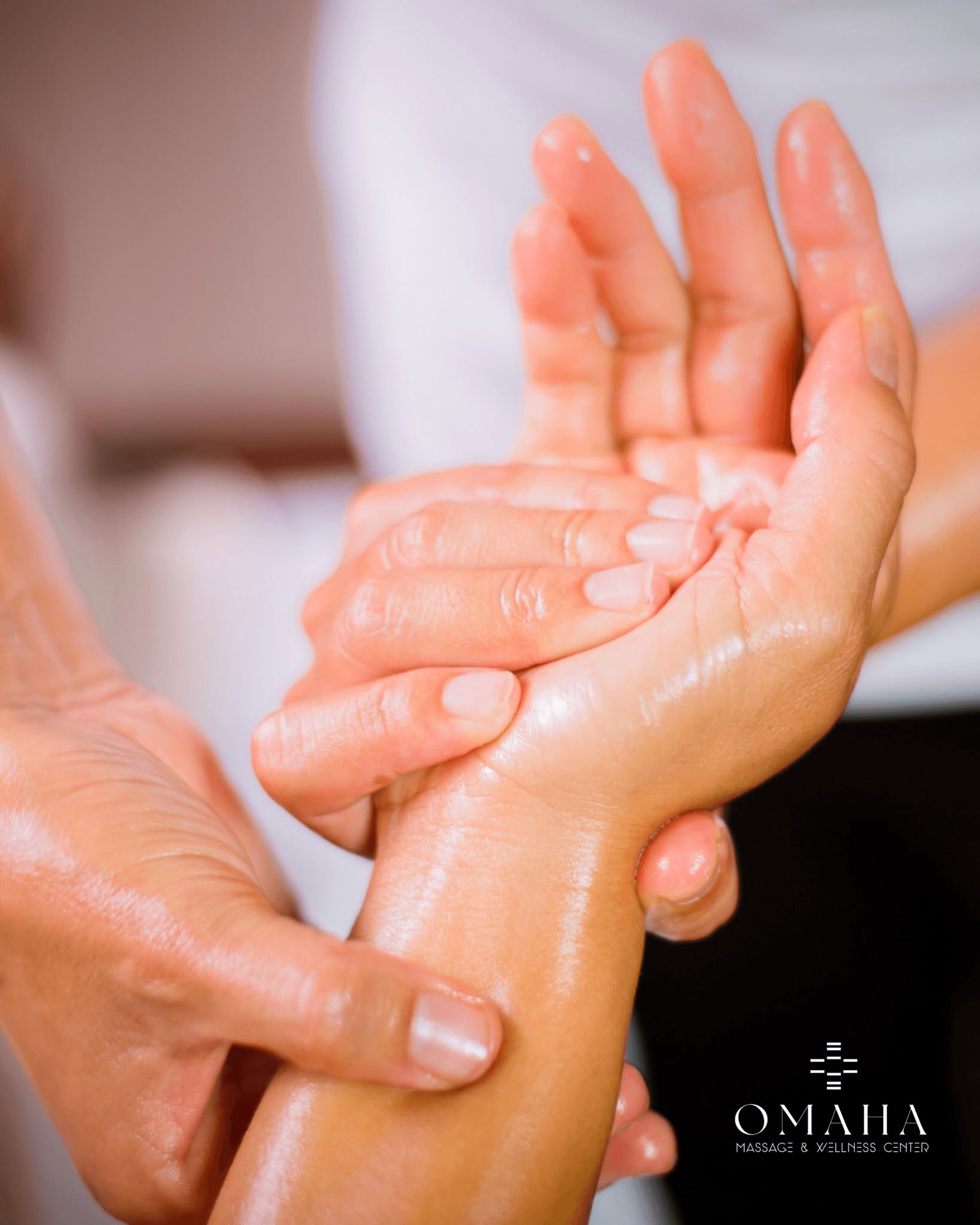 Massage therapist applying targeted thumb pressure to a client’s palm and wrist during a medical massage in Omaha